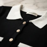 Woman wearing a premium LÉON KNITS black cardigan with a white Peter Pan collar and gold buttons in a luxury interior (1)