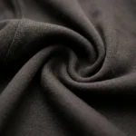 Woman wearing a premium LÉON KNITS black cardigan with a white Peter Pan collar and gold buttons in a luxury interior (4)