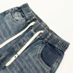 Light blue acid wash baggy jogger jeans with dark blue side panels and white drawstrings (2)
