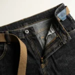 Men's dark wash slim fit indigo denim jeans with khaki webbed belt and white sneakers (4)