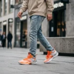 Men's high top basketball shoes in vibrant orange and silver grey with wavy traction sole