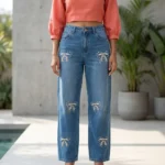 Women's high waisted blue jeans featuring white pearl and rhinestone bow patterns on the front legs (1)