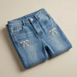 Women's high waisted blue jeans featuring white pearl and rhinestone bow patterns on the front legs (2)