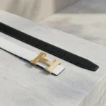 a white textured leather belt with a gold H shaped buckle (2)
