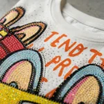 women's white oversized t shirt featuring a colorful animated character print and iridescent rhinestone detailing (3)