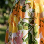 Full length front view of a woman wearing a sleeveless yellow and orange floral maxi dress with a deep V neck and cutout detail (1)
