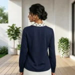 woman wearing an ivory formal blouse with a beige polka dot neck tie and pearl ring.