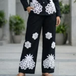 woman wearing a black co ord set with white floral embroidery, highlighting the button down shirt design (3)