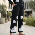 woman wearing a black co ord set with white floral embroidery, highlighting the button down shirt design (4)