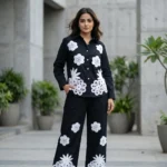 woman wearing a black co ord set with white floral embroidery, highlighting the button down shirt design (6)