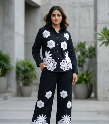 woman wearing a black co ord set with white floral embroidery, highlighting the button down shirt design (6)