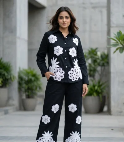 woman wearing a black co ord set with white floral embroidery, highlighting the button down shirt design (6)