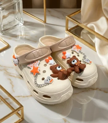 Women cream chunky clogs with brown bear charms, orange stars, and a silver chain strap (1)
