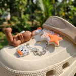 Women cream chunky clogs with brown bear charms, orange stars, and a silver chain strap (3)
