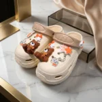 Women cream chunky clogs with brown bear charms, orange stars, and a silver chain strap (4)