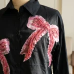 Women wearing a black crop shirt with pink beaded bow design (3)